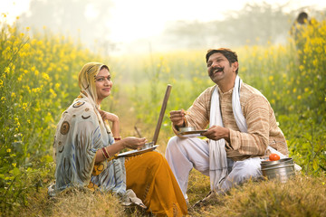 Wall Mural - Rural couple having lunch break on agriculture field