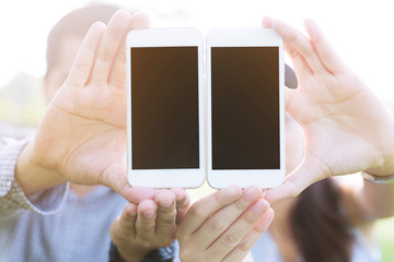 close up of two young male and female hand holding display white mobile smart phone with blank of em