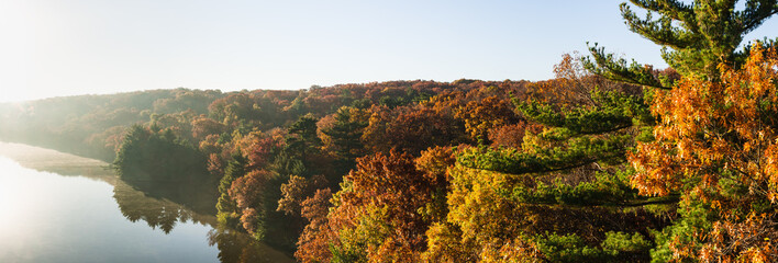 Autumn colors on the Illinois River as the morning sun lights up the tree tops.  Starved Rock State Park, Illinois, USA