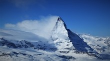 A Wonderful Panoramic  Image Of The North Face Of The World Famous Matterhorn Partly Covered In Clouds On A Further Clear Day In The Ski Area Of Zermatt In The Swiss Alps