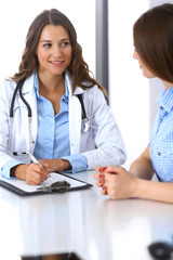 Doctor and  happy patient  talking while sitting at the desk. The physician or therapist discussing healthy lifestyle. Health care, medicine and patient service concept