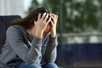 Sad woman complaining alone on a couch at home