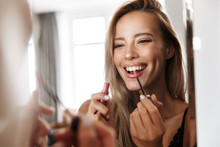 Young Woman In Lingerie Underwear Looking At Mirror Apply Her Lipstick Lip Gloss Doing Makeup.