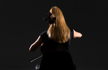 Wall Mural - Young girl playing the cello on isolated black background