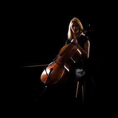 Wall Mural - Young girl playing the cello on isolated black background