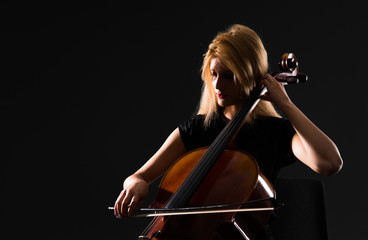 Wall Mural - Young girl playing the cello on isolated black background