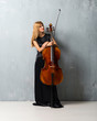 Young blonde girl with her cello on textured wall background
