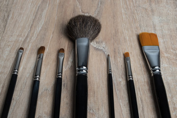 Set of brushes for makeup on wooden background. Fashion makeup brushes.