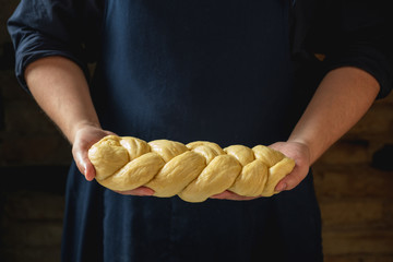 Wall Mural - Male baker holding loaf of raw challah jewish bread