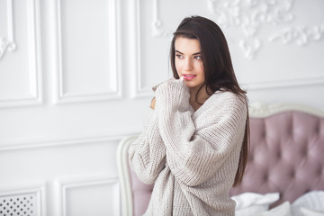 Wall Mural - Young attractive woman indoors. Girl on neutral background. Happy woman. Female in the bedroom at home. Close up portrait of beautiful lady.