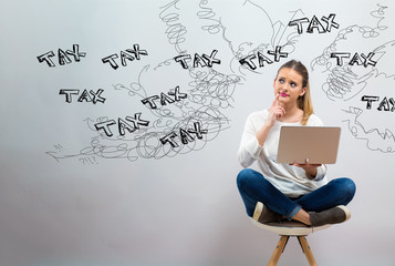 Wall Mural - Tax problem theme with young woman using her laptop on a grey background