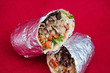 Burrito Wrapped in Aluminum Foil on a red background