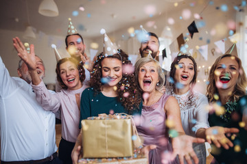 A portrait of multigeneration family with presents on a indoor birthday party.