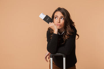 Sticker - Confused young woman posing isolated holding passport with tickets and suitcase.