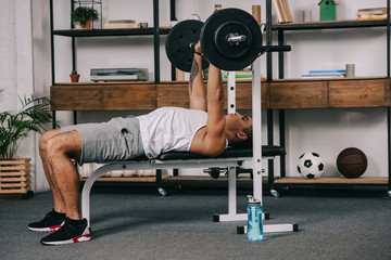 Wall Mural - muscular mixed race man workout with barbell in home gym