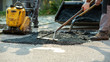 Low angle view of two workers arranging fresh asphalt mix with rakes and shovel
