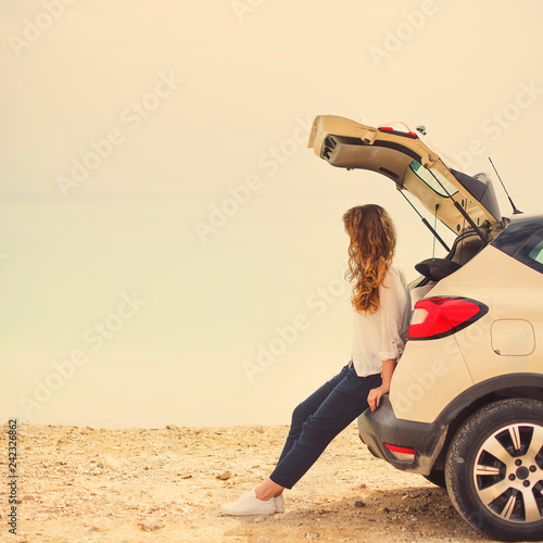 Happy Stylish Young Woman Traveler On Beach Road Sitting On White