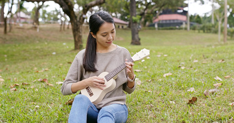 Poster - Asian Woman enjoy play ukulele and song in the park