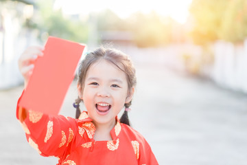 4 years old asian chinese child girl receive money from her mother.Happy Little asian girl in chinese traditional dress smiling and holding red envelope.Happy chinese new year concept.