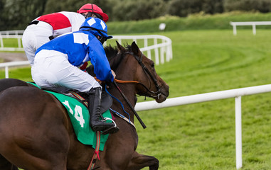 Close-up action on two race horses and jockeys galloping for position.