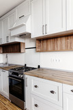 Fototapeta Panele -  Luxury modern kitchen furniture in grey color and steel oven,fridge, sink, wooden tabletop. Gray cabinets in scandinavian style. Home renovation. Stylish kitchen interior design.