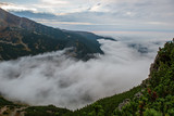 Fototapeta Miasto - large misty cloud climbing mountain valley in slovakia, Tatra