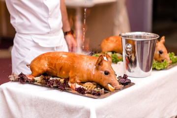 Roast pig. Roasted piglet with vegetables on platter