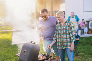 Picture of middle age couple making barbeque in their backyard. Family lunch on summer day.