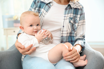 Poster - Lovely mother giving her baby drink from bottle in room