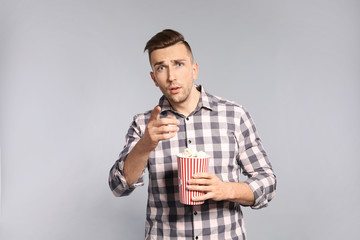 Canvas Print - Emotional man with popcorn during cinema show on grey background