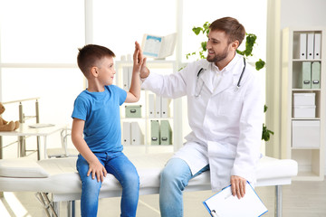 Wall Mural - Children's doctor giving high five to patient in hospital