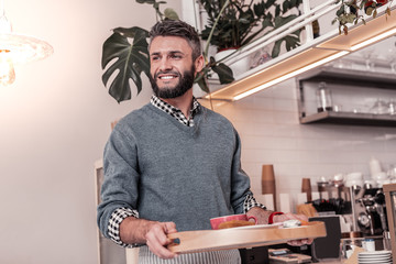 Joyful pleasant man bringing order to the table