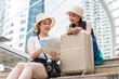 © phichak - Young Asian tourist women wearing hats looking for direction from a map with smiling faces