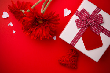 Wall Mural - Gift, red gerberas and a heart on a red background.