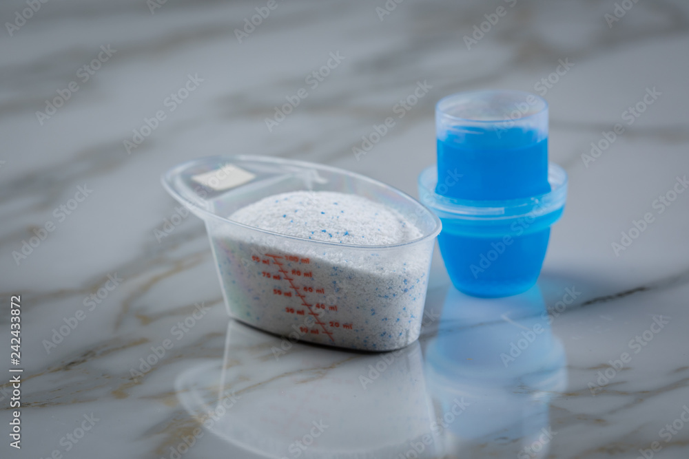 Stock-Foto „Waschmittel Pulver und blaues Flüssig Gel in Dosierung Messbecher “