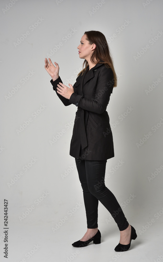 full length portrait of a brunette girl wearing long black coat ...