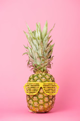 Wall Mural - funny and tasty pineapple in sunglasses on pink background