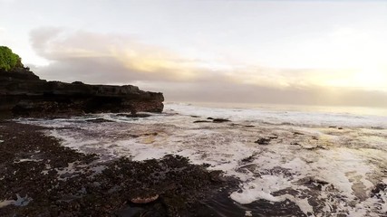 Wall Mural - A video from the ocean wavy coast of topical Bali island camera moving down to up, sunset time.