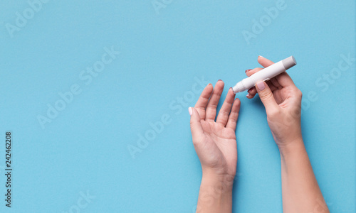 Fotografía Woman using glucometer on blue background, top view