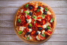  Pizza With Pepperoni, Tomatoes, Cheese, Olives And Basil. Delicious Pizza Served On Wooden Plate On Rustic Background. Overhead, Horizontal