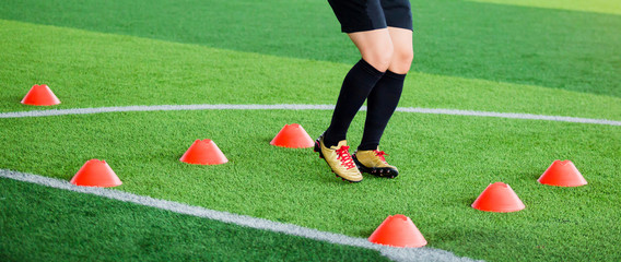 Wall Mural - Soccer player Jogging and jump between cone markers on green artificial turf for soccer training