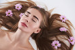 © Yakobchuk Olena - Attractive young lady with flowers in her hair lying on white background