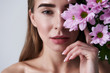 © Yakobchuk Olena - Attractive young woman covering eye with beautiful pink flowers