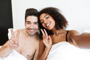 Poster - Beautiful happy young multiethnic couple relaxing in bed