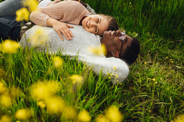 Wall Mural - beautiful young couple lying in green grass