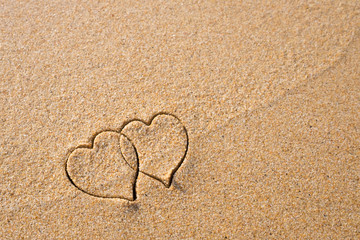 Two hearts drawn in the sand at the beach.