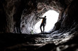 Silhouette of Young explorer in black sportswear in a cave with climbing equipment ready for action