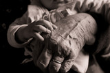 Fototapeta  - small baby hand touching and caressing old grandmother hand with wrinkles, symbol of passing generations