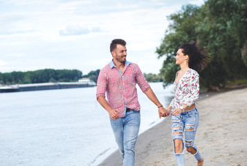 Romantic young couple having fun on the beach embracing and holding hands.