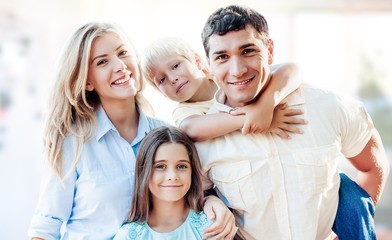 Wall Mural - Beautiful smiling family sitting at sofa on background